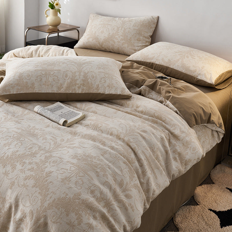 Damask jacquard bedding styled with layered pillows in a calm, neutral bedroom setting.