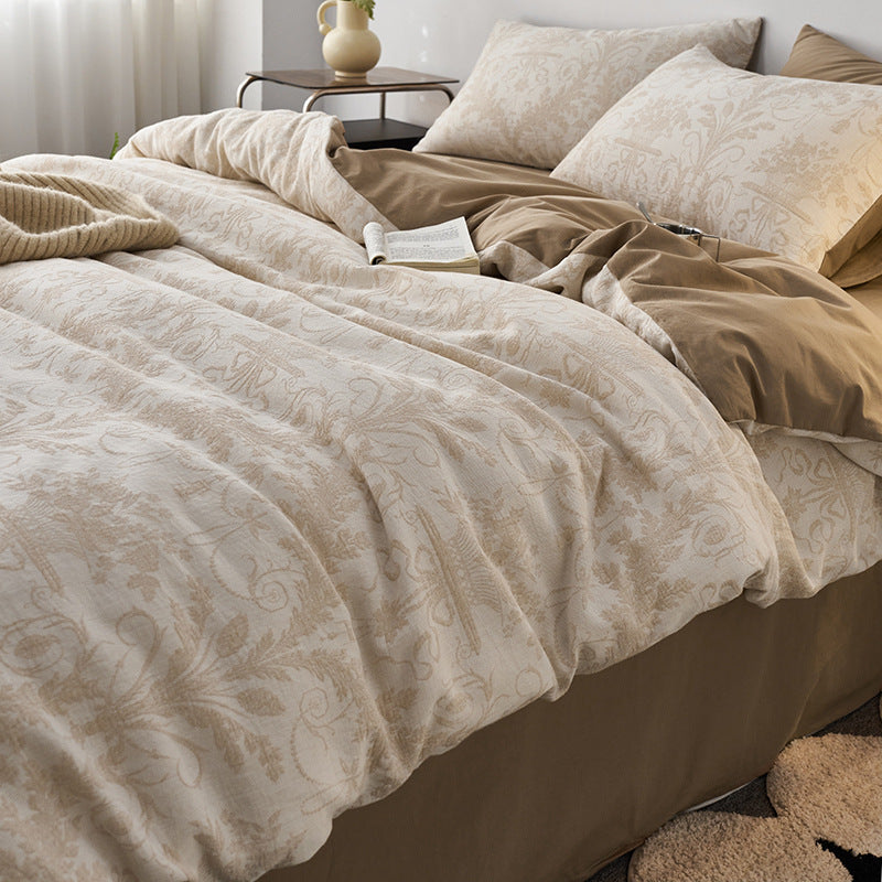 Close view of woven damask jacquard bedding in soft neutral tones with layered pillows.