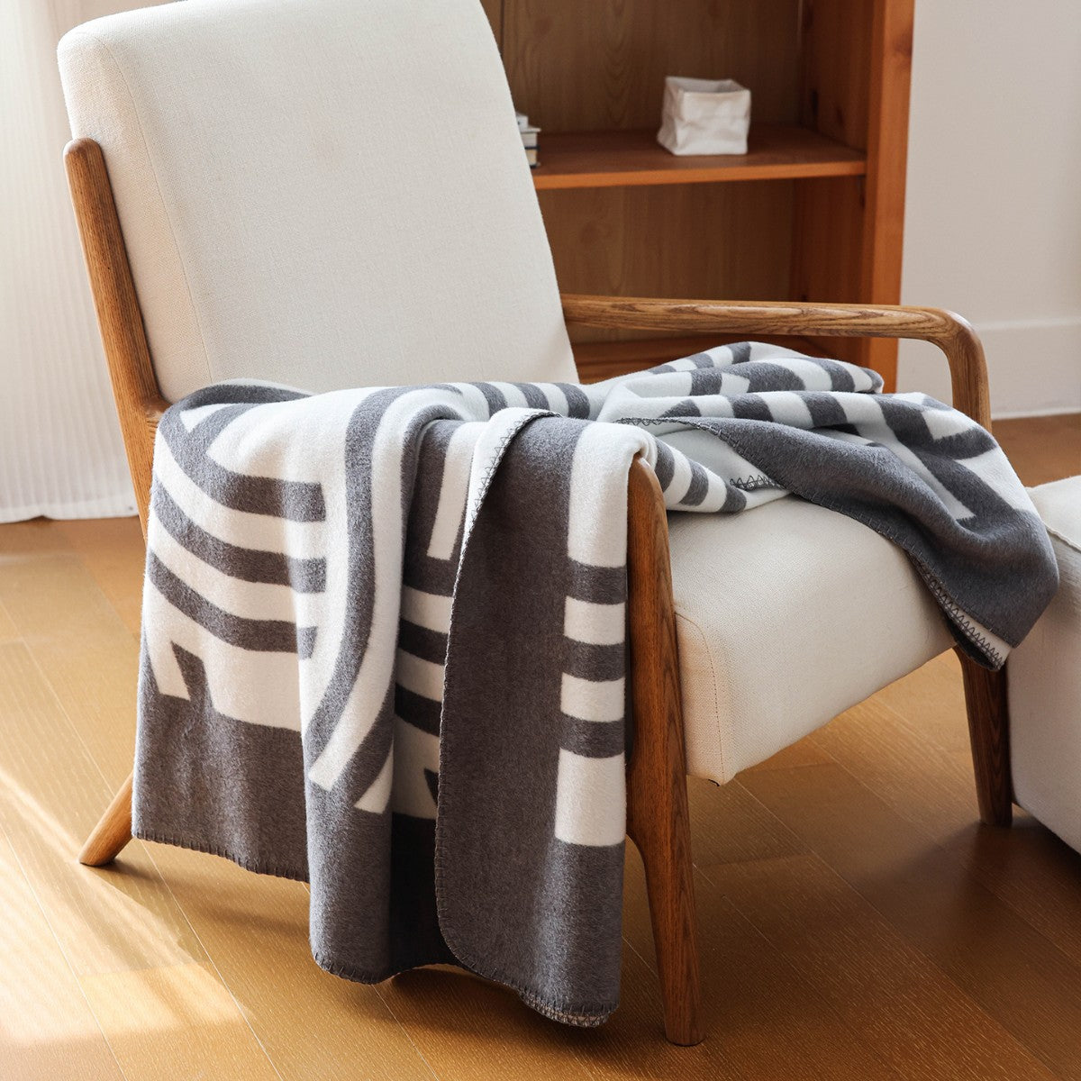 Berriscent geometric woven throw in grey and ivory draped over a wooden armchair, styled in a calm, modern living space.
