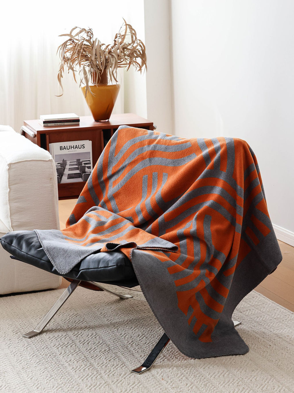 Geometric woven throw draped over a modern lounge chair in a light-filled living room.
