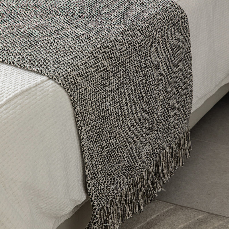 Textured cotton bed runner in graphite tones with soft fringe detail.