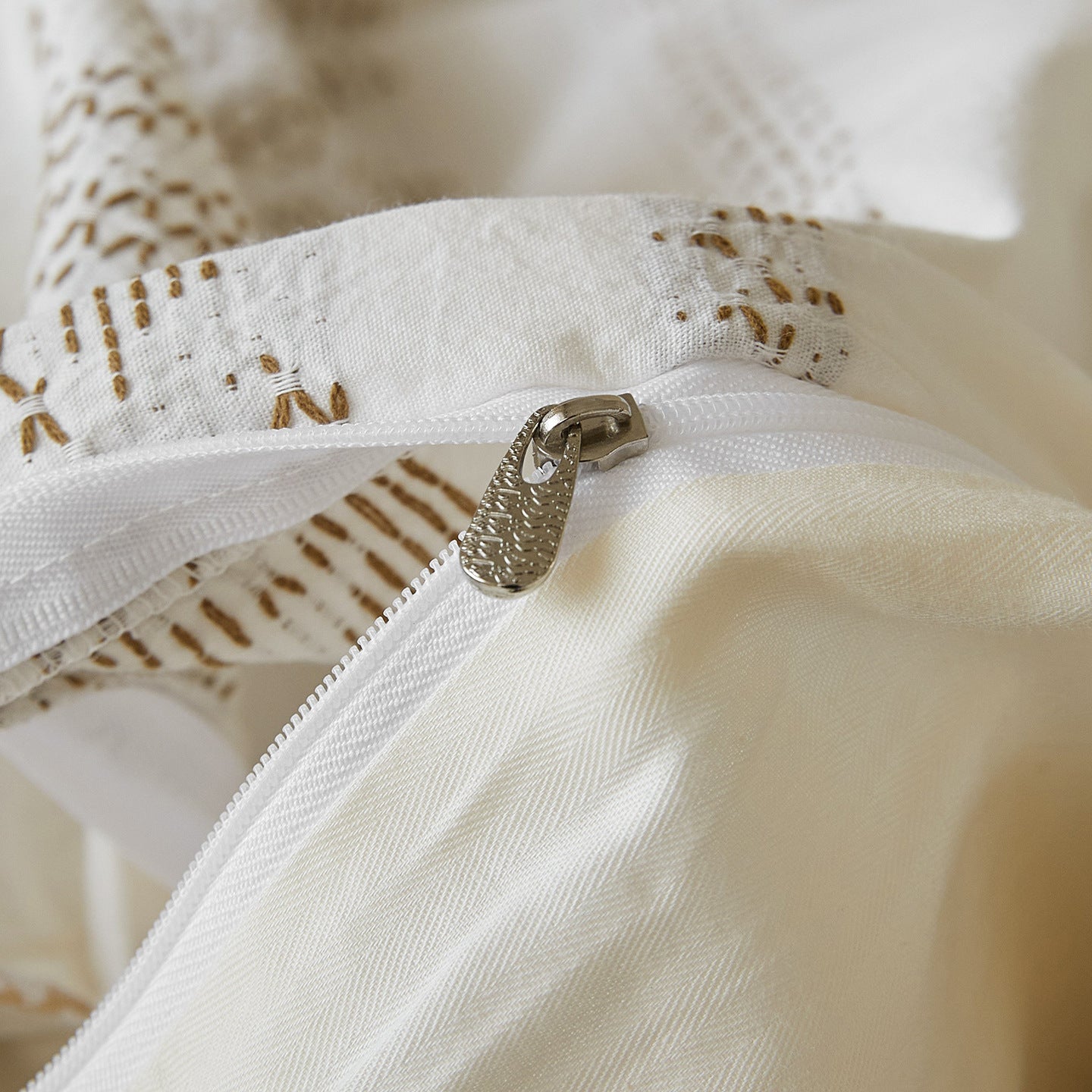 Detailed shot of a high-quality hidden metallic zipper closure on a premium white jacquard duvet cover.
