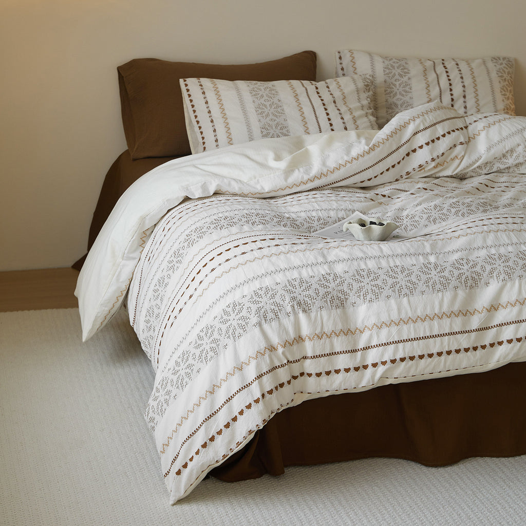 Side view of a thick, woven cotton duvet cover showing the layered texture and draped cocoa-colored flat sheet.