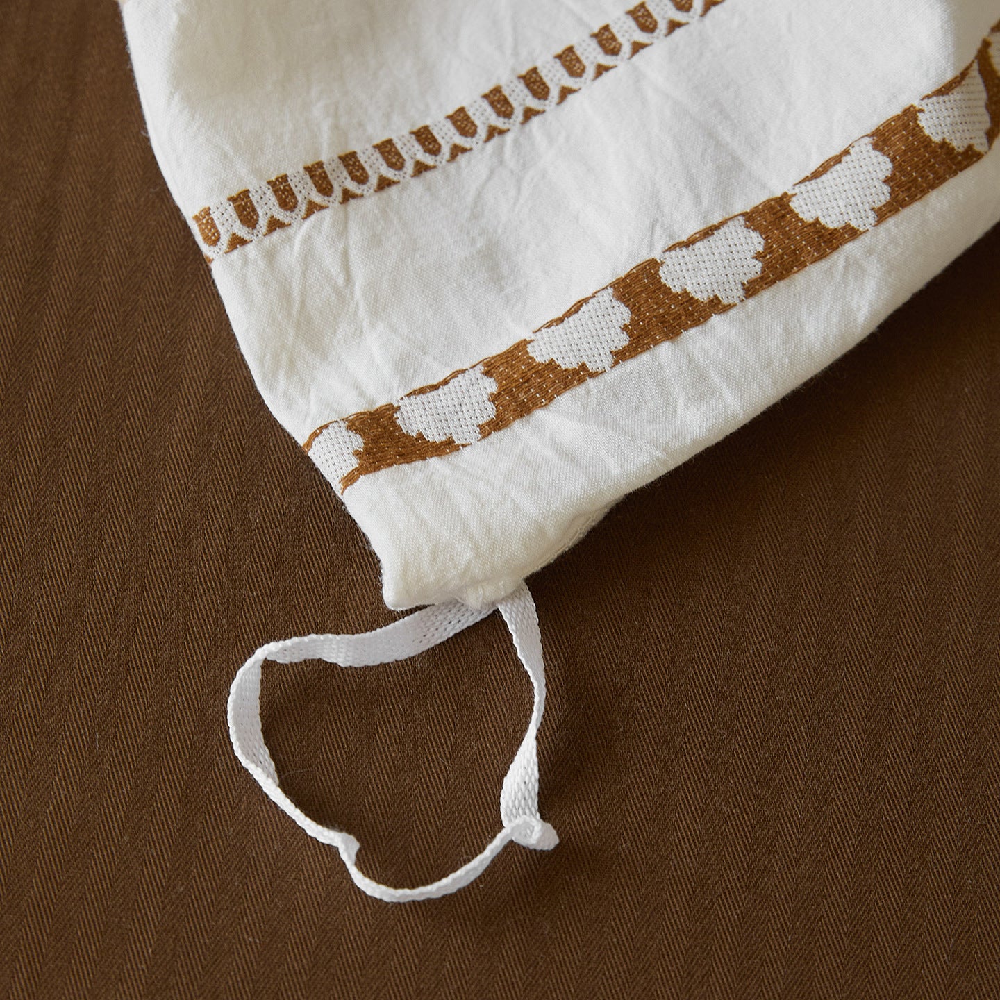 Macro detail of the jacquard weave pattern showing the heart and chevron borders woven directly into the 100% cotton fabric.